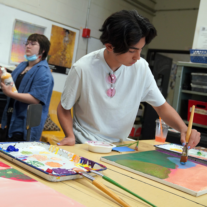 student in class painting on canvas.